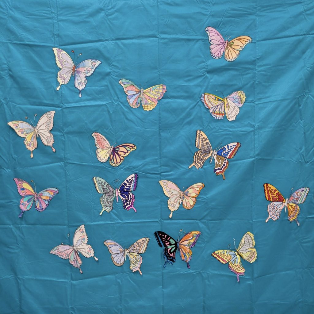 Paper butterflies hanging on a blue sheet background.
